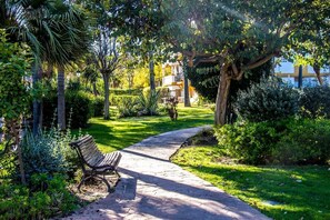 Stroll through the serene garden, lined with lush greenery and mature trees, to a inviting bench.