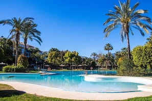 Relax by the resort pool surrounded by lush greenery and a lifeguard stand.