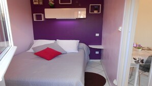 A small, neatly arranged bedroom with a bed, a nightstand, and a chair. - Charming little Gite C (Sotteville-lès-Rouen)