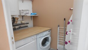 A laundry room with a washing machine, a drying rack, and a shelf with a box labeled "Rowenta." - Charming little Gite C (Sotteville-lès-Rouen)