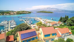Eine Küstenstadt mit einem Yachthafen, Häusern mit roten Dächern und einem Berg im Hintergrund.