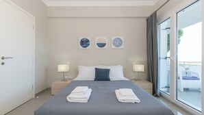 Una habitación de hotel con una cama grande, dos mesitas de noche con lámparas, vistas al exterior y tres obras de arte en la pared.