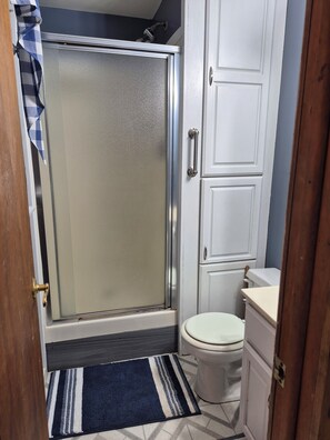 Un baño con ducha, inodoro y armarios.