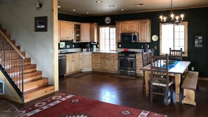 A spacious kitchen with wooden cabinets, a stainless steel stove, and a dining area with a wooden table and chairs.