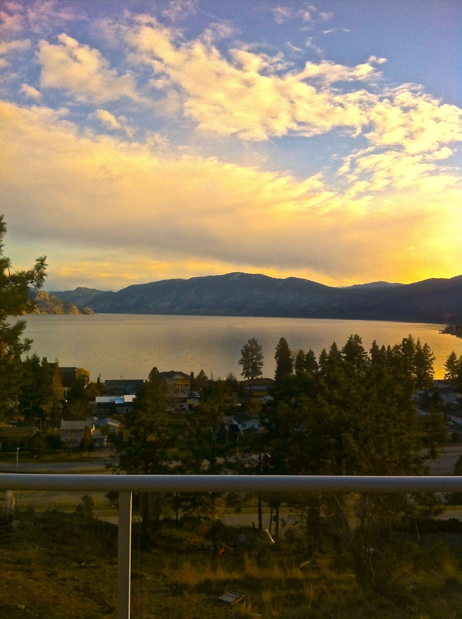 A lake with mountains in the background and a residential area in the foreground.