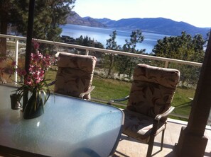 A balcony with two chairs and a table, overlooking a lake and mountains. - Beautiful 750sqf private suite..Spectacular view, close to downtown! (Peachland)