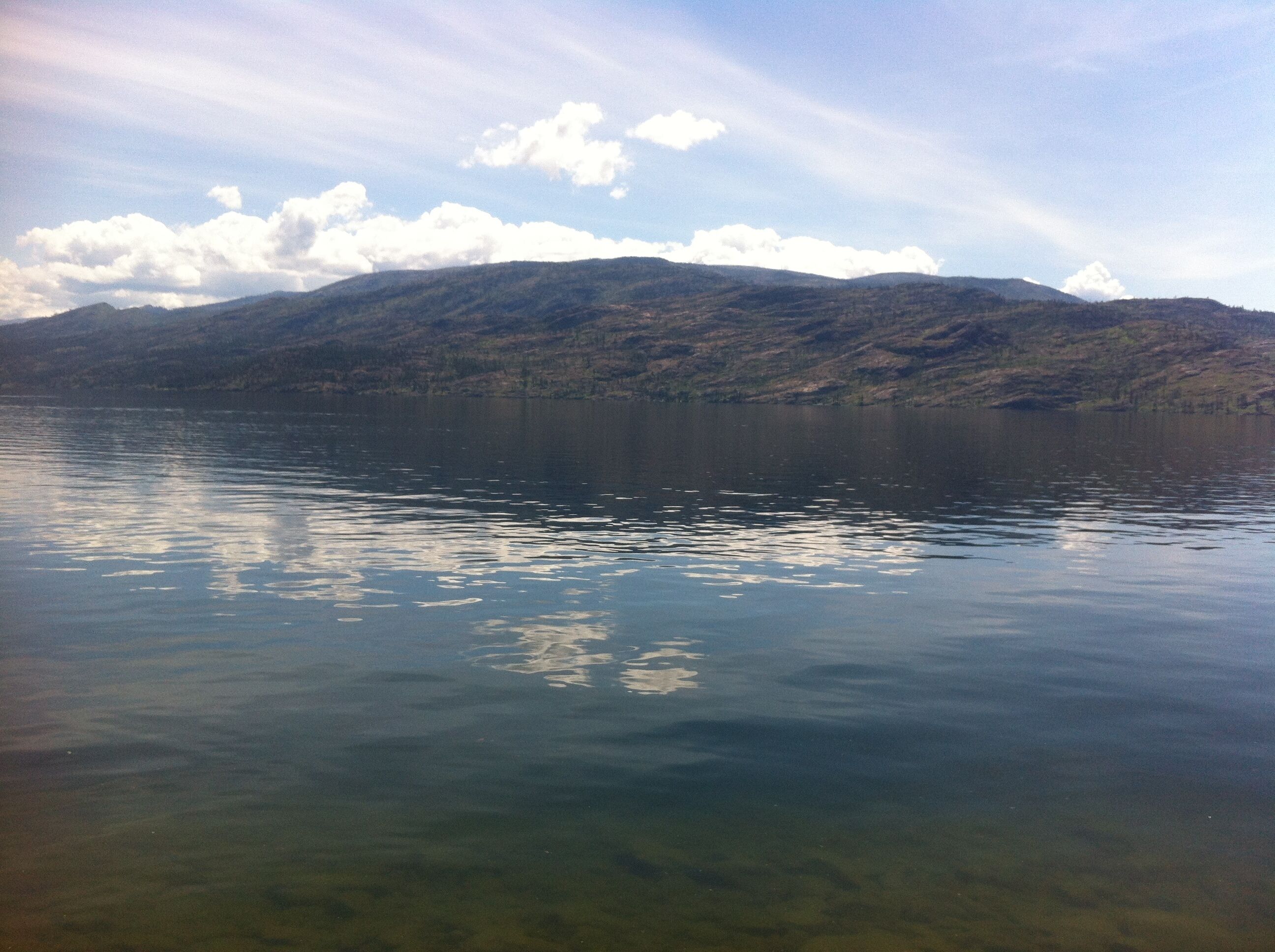 Un lago tranquilo con montañas al fondo.