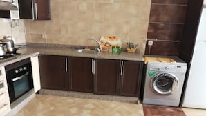 Una cocina con armarios marrón oscuro, encimera de granito, horno empotrado, lavabo y lavadora de carga frontal.