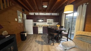 Una cocina acogedora con armarios de madera, una estufa y una mesa de comedor con sillas.