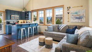 Una cucina moderna con mobili blu scuro, un'isola centrale con sgabelli e un'ampia finestra con vista sulle montagne.