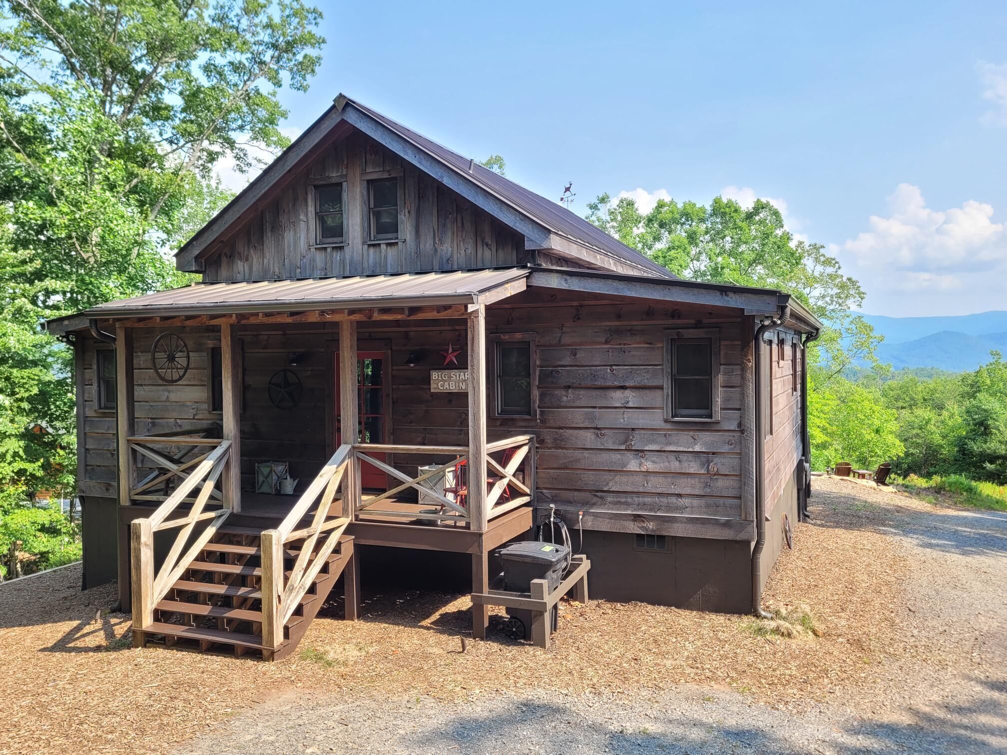 Un chalet rustique doté d’une véranda, d’un petit escalier et d’une enseigne indiquant : « Big Star Cabin ».