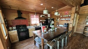 Una cucina rustica con mobili in legno, un fornello e un'area pranzo con sedie in metallo.