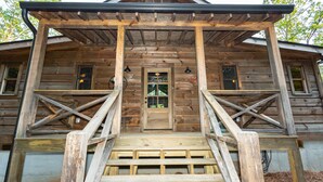 Una baita di legno con un portico, una porta centrale e due finestre.