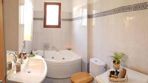 A bathroom with a bathtub, a sink, a toilet, and a mirror.