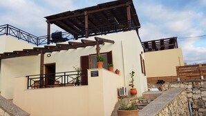A building with a stone wall, a wooden pergola, and a sign reading "Sharon's Stone Villa".