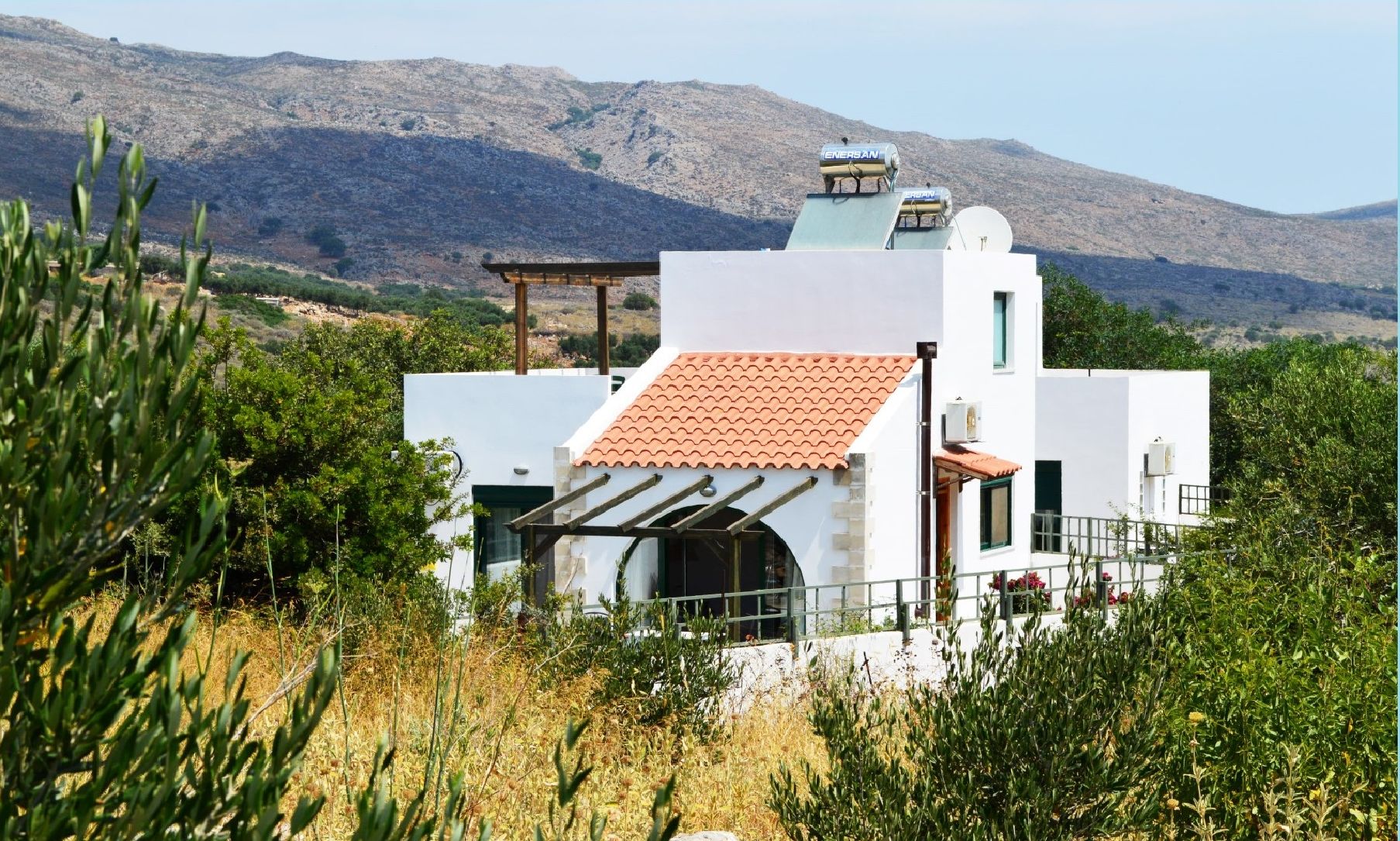 A modern building with a white facade, a red-tiled roof, and a satellite dish.