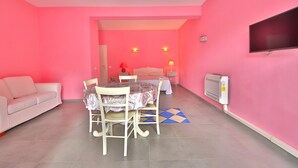 A pink-themed room with a sofa, dining table, chairs, a TV, and a ceiling fan. - NARCISO by KlabHouse-2pax w/AC&terrace walk2beach (Sciacca)