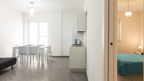 Een moderne, goed verlichte kamer met een eethoek, kitchenette en een bed.