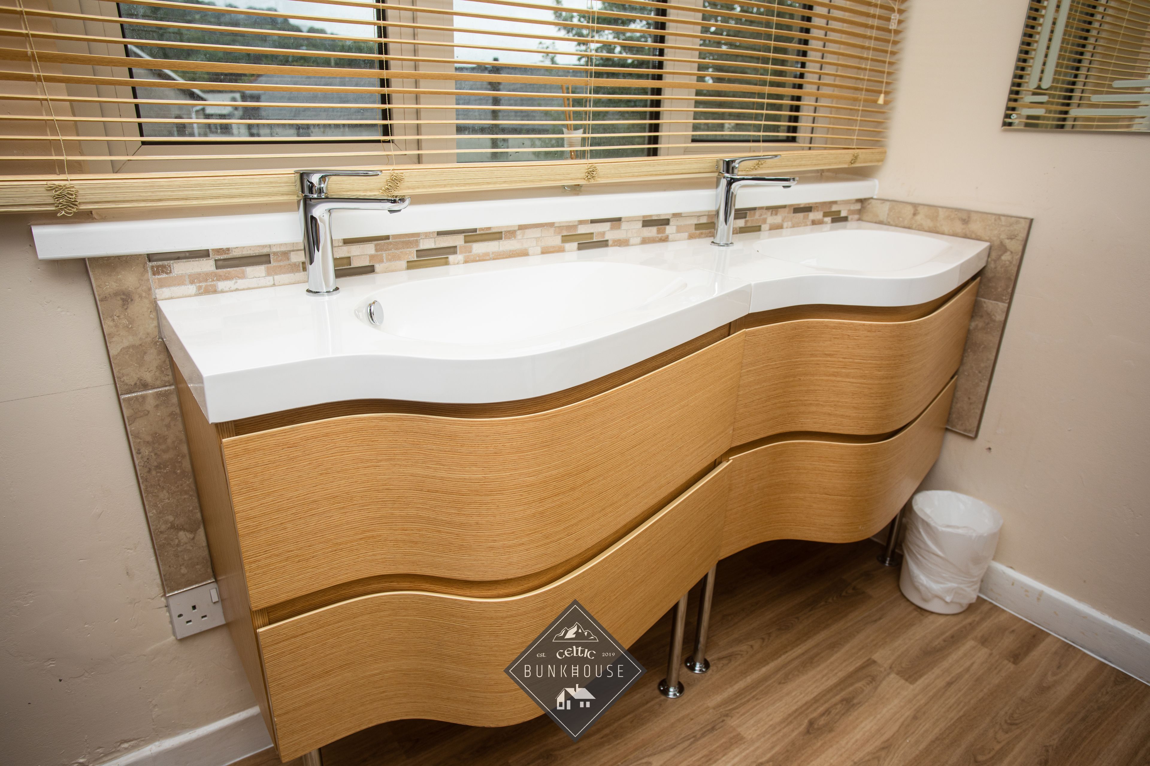 A bathroom with a wooden vanity, two sinks, and a mirror above.