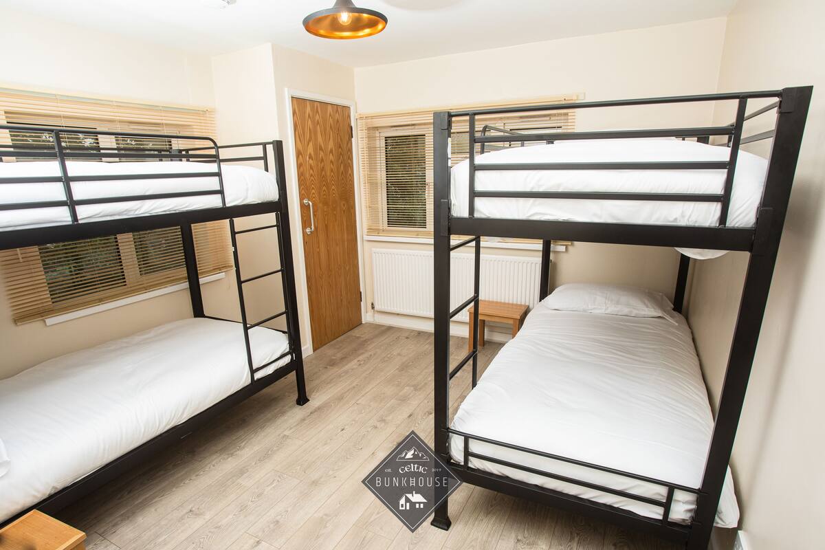 A room with bunk beds, wooden flooring, a radiator, and a door.