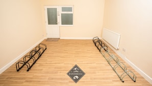 A room with a wooden floor, a white door with a window, and a radiator on the wall. - Celtic Bunkhouse Hostel (Merthyr Tydfil)