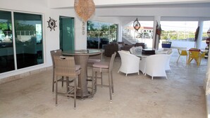 A spacious living area with a round table and chairs, a sofa set, and a large window offering a view of the outside.