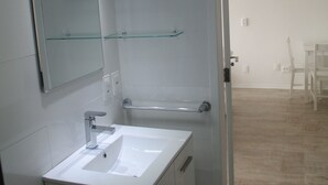Une salle de bain moderne avec un lavabo blanc, un miroir et des étagères en verre.