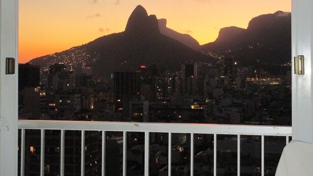 Une vue urbaine avec la silhouette d’une montagne imposante au coucher du soleil.