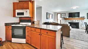 A modern kitchen with wooden cabinets, a built-in microwave, and a granite countertop. - Canyons Mountain Views 2 br across from Resort (Park City)