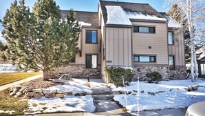 A two-story residential building with a stone foundation, a sloped roof, and a front entrance with a stone pathway leading to the door. - Canyons Mountain Views 2 br across from Resort (Park City)