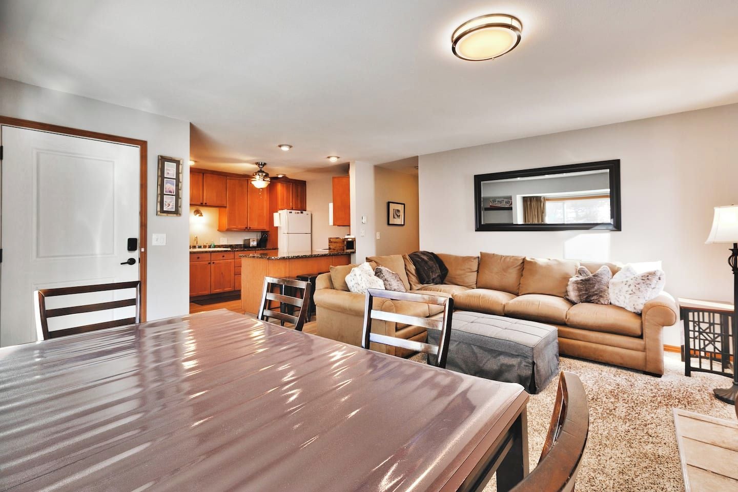 A modern living room with a dining table, a sofa, and a kitchen in the background.