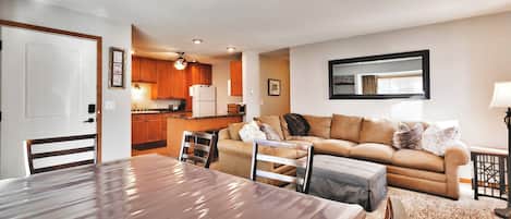 Una sala de estar moderna con una mesa de comedor, un sofá y una cocina al fondo.