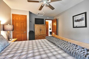 Une chambre à coucher avec un lit, une armoire, un ventilateur de plafond et un tableau encadré au mur.