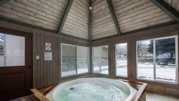 A wooden cabin with a hot tub, large windows, and a snowy outdoor view. - Canyons Mountain Views 2 br across from Resort (Park City)
