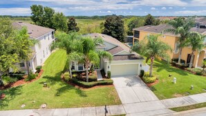 A residential neighborhood with houses featuring front yards, palm trees, and a clear sky. - LUXE DISNEY HOME, POOL W/ SPA, GAME ROOM,  FREE NETFLIX & WIFI  (Davenport)