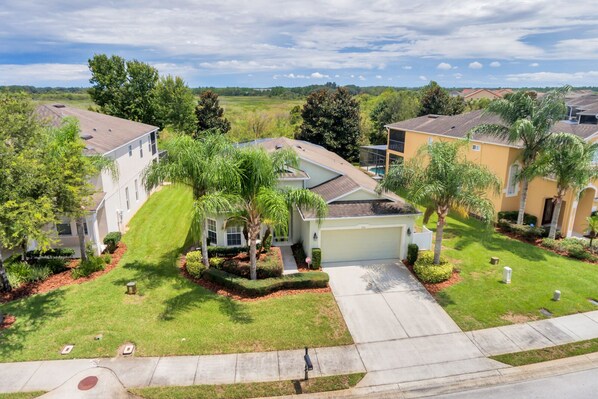A residential neighborhood with houses featuring front yards, palm trees, and a clear sky.