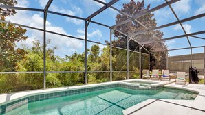 A covered outdoor swimming pool with clear blue water, surrounded by lounge chairs and a pergola structure. - LUXE DISNEY HOME, POOL W/ SPA, GAME ROOM,  FREE NETFLIX & WIFI  (Davenport)