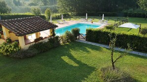 Zona de piscina con estructura cubierta de tejas, una pileta y abundante vegetación circundante.