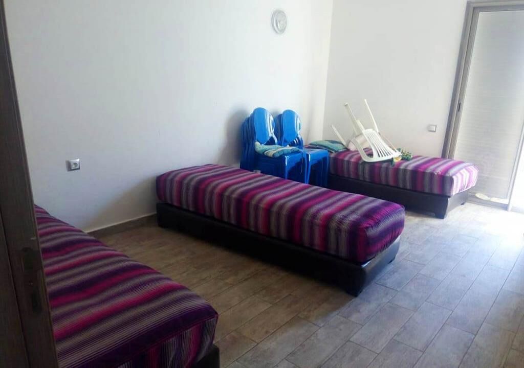 A room with two single beds, a chair, and a bench.