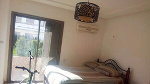 Un dormitorio con cama, una silla, un patinete y una ventana con vista a zonas verdes.