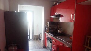 Una cocina con gabinetes rojos, un refrigerador negro y una estufa.