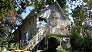A two-story house with a balcony, a wooden deck, and a picnic table.