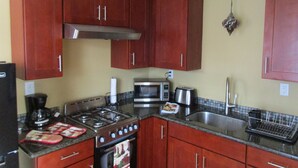 A kitchen with wooden cabinets, a gas stove, a microwave, and a sink.