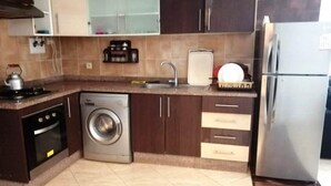 A compact kitchen with a washing machine, a refrigerator, and a sink. - Nice apartment in Essaouira 4267 (Essaouira)