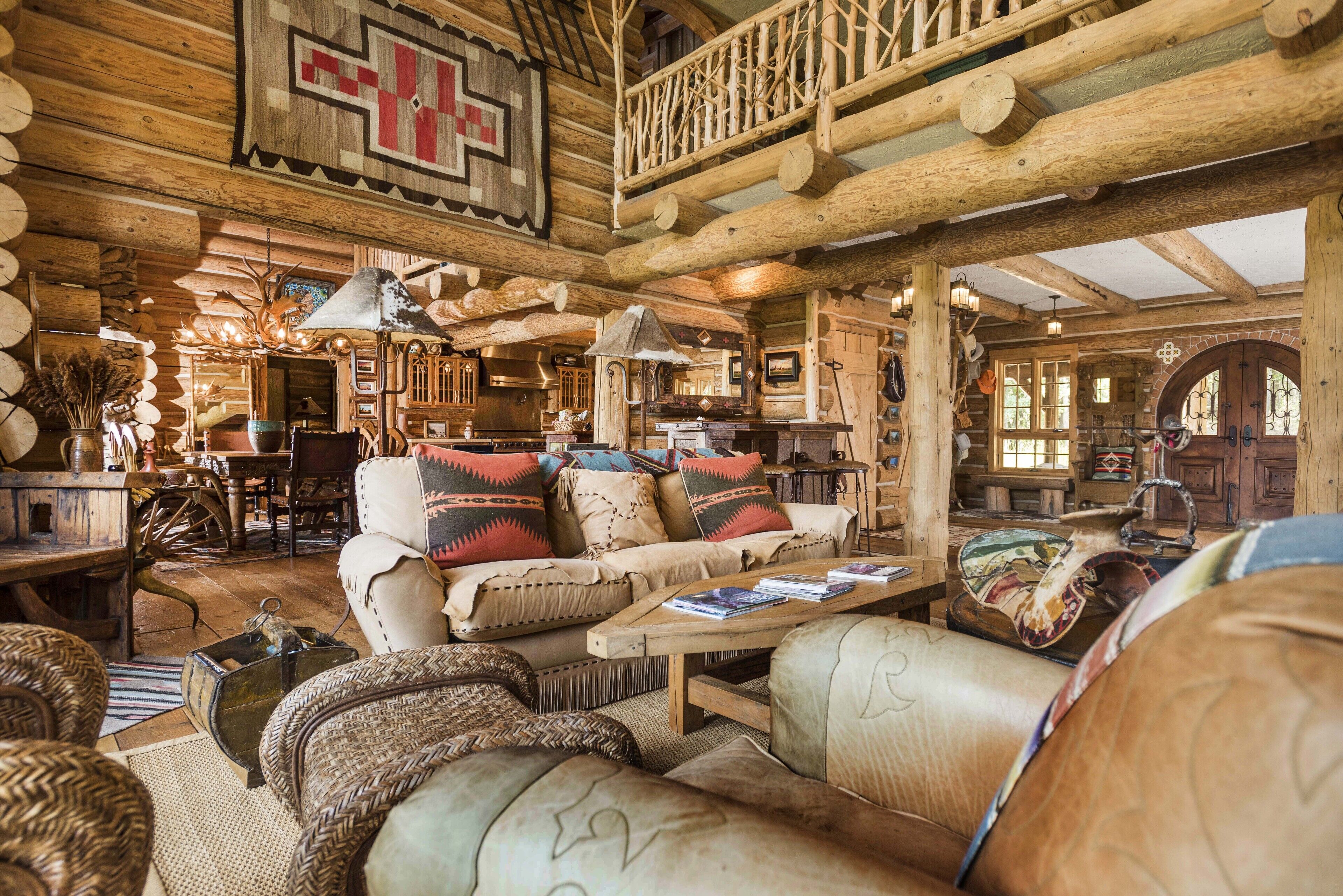 Interior de una cabaña de troncos con una sala de estar acogedora que incluye un sofá, una mesa de centro y decoración rústica.