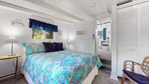 A bedroom with a large bed, a bedside table, a chair, and a window with a view. - Holiday Hill Resort  "The Treehouse" Unit 722 (Saugatuck)