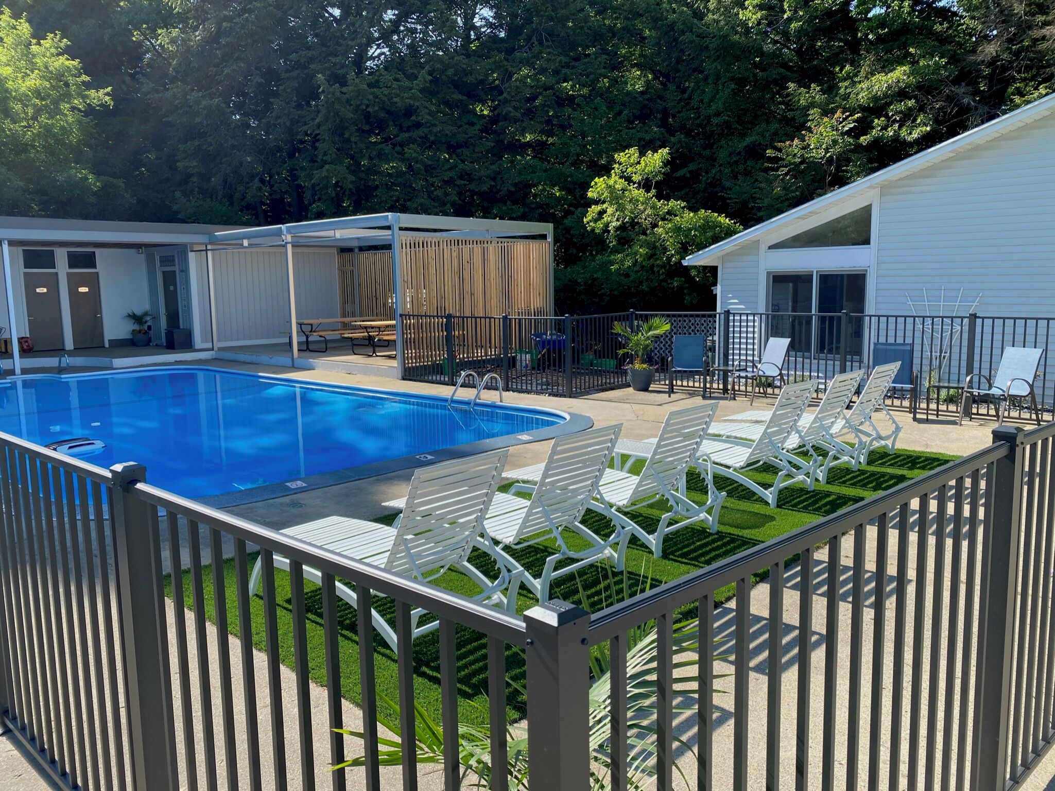 A swimming pool with lounge chairs and a covered patio area.
