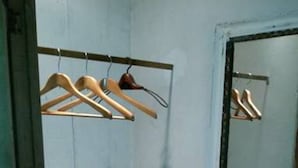Ein kleiner, schummrig beleuchteter Raum mit einer Tür und einem an der Wand befestigten Kleiderständer.