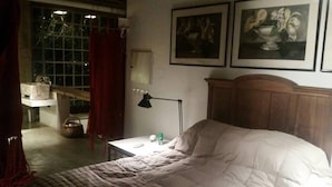 Ein Schlafzimmer mit einem großen Bett, einem Nachttisch mit Lampe und zwei gerahmten Bildern an der Wand.