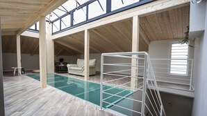 A spacious indoor area with a glass-bottomed pool, wooden flooring, and a white metal ladder. - Le Fontanelle B&B (Sarno)